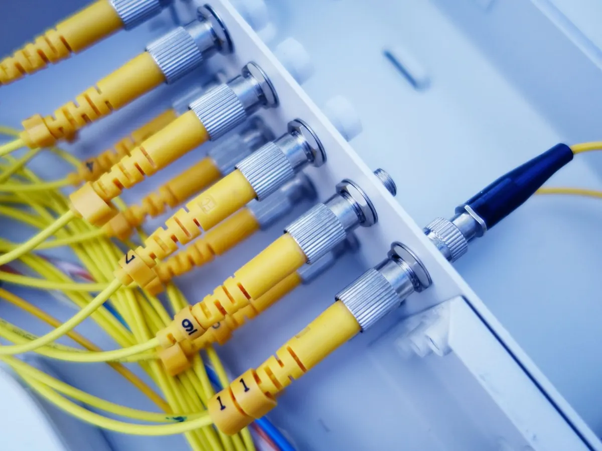 Cordões de fibra óptica amarelos com conectores ligados a um distribuidor óptico